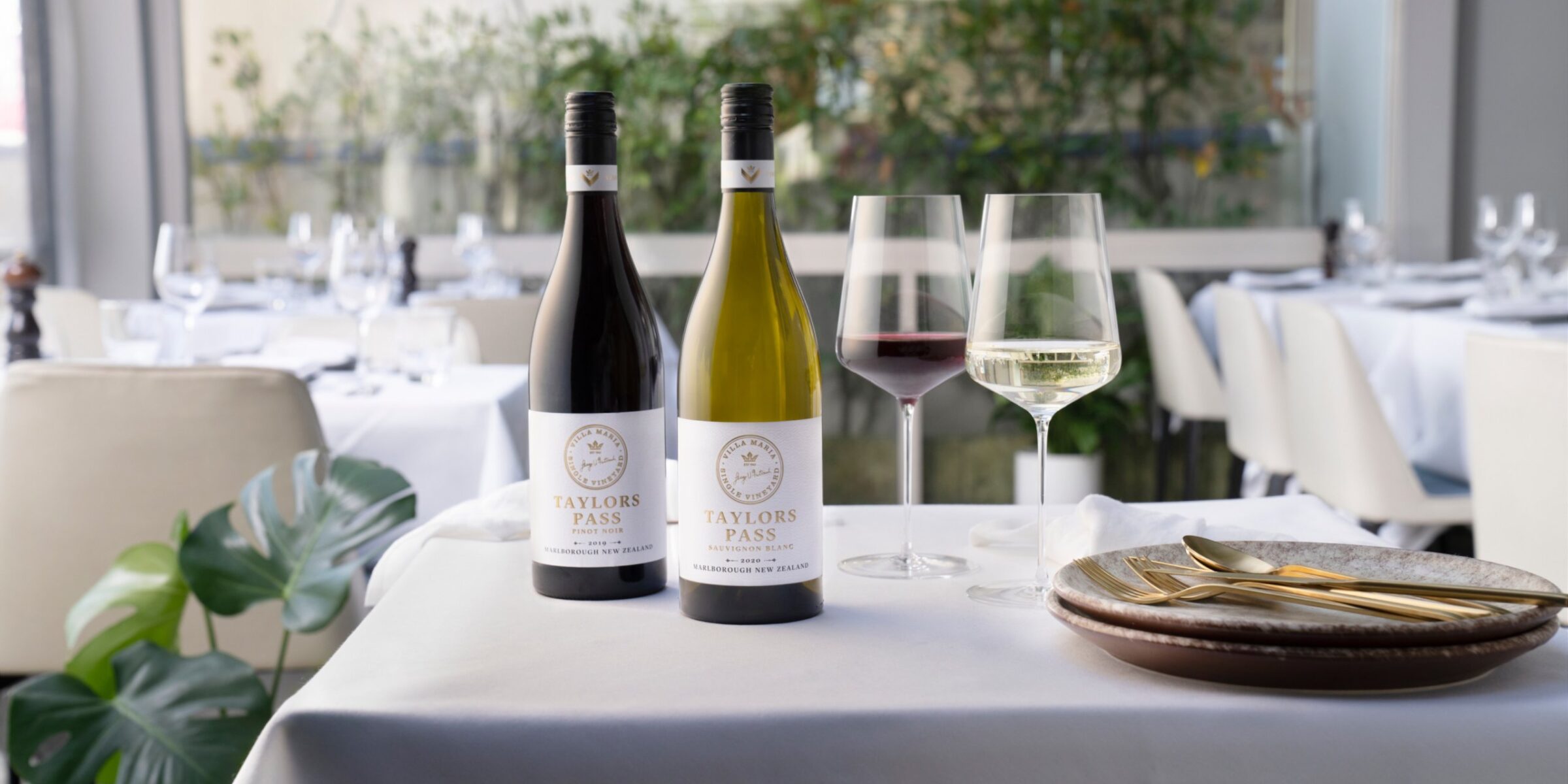 Bottles and glasses of wine on a table in a dining room.