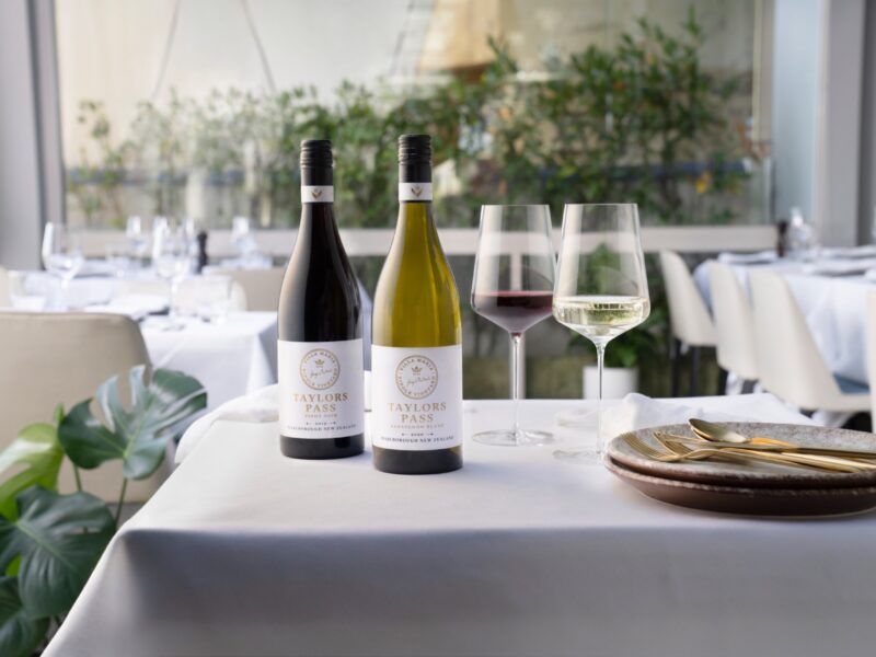 Bottles and glasses of wine on a table in a dining room.