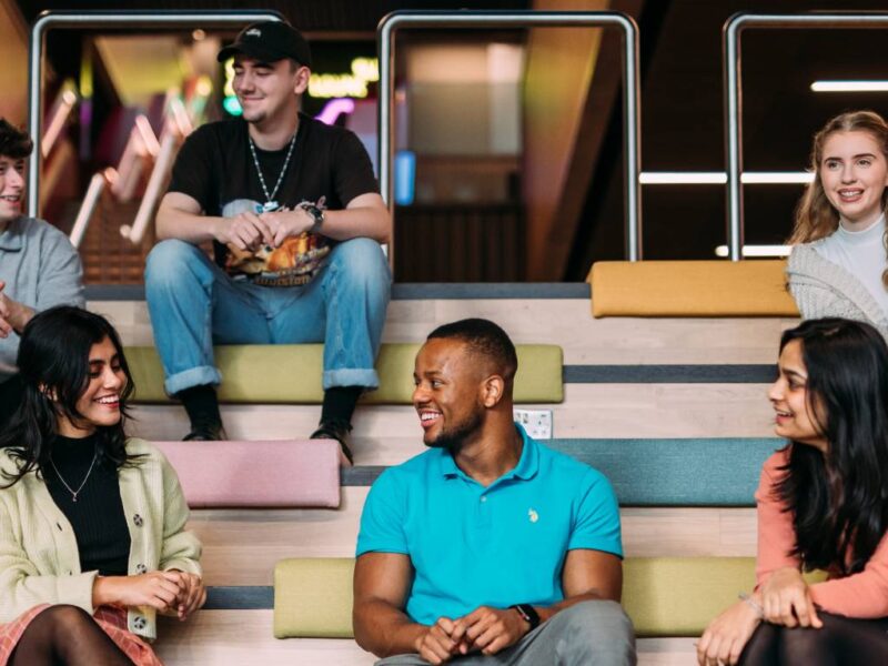 Students sit on steps chatting and smiling