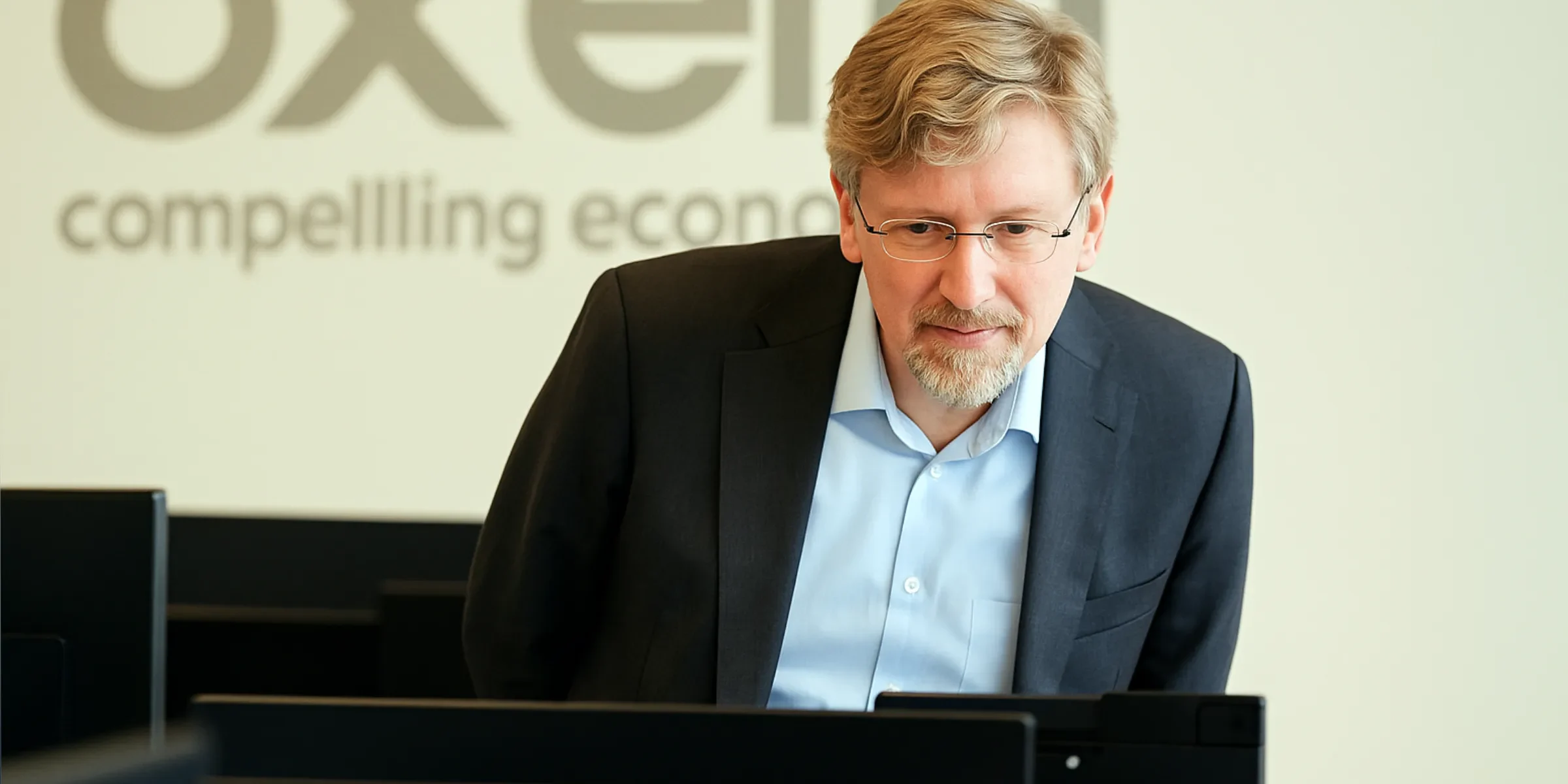 Economist looking at a screen with oxera logo in background