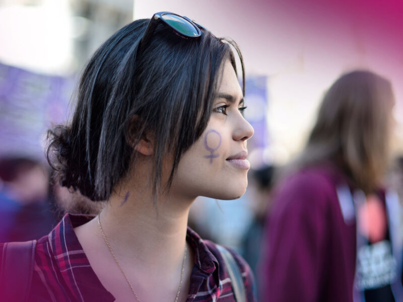 A young woman with a female symbol drawn on her face
