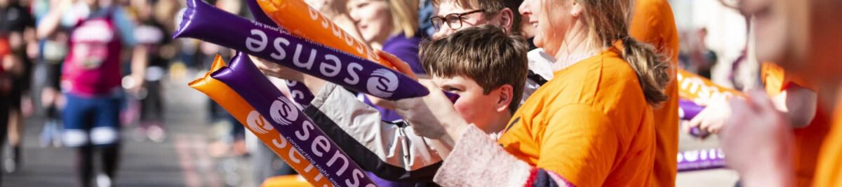 Sense charity supporters holding coloured inflatable batons