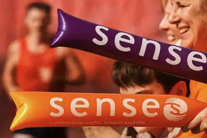 People smiling at a charity event holding Sense balloons for awareness.