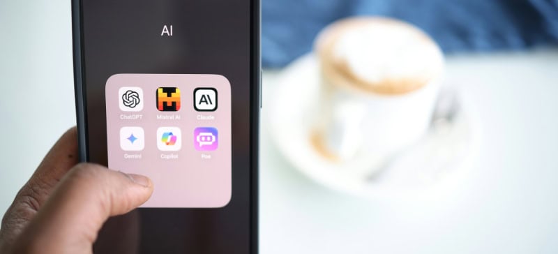 Mobile phone screen showing icons of AI apps installed, and a cup of coffee