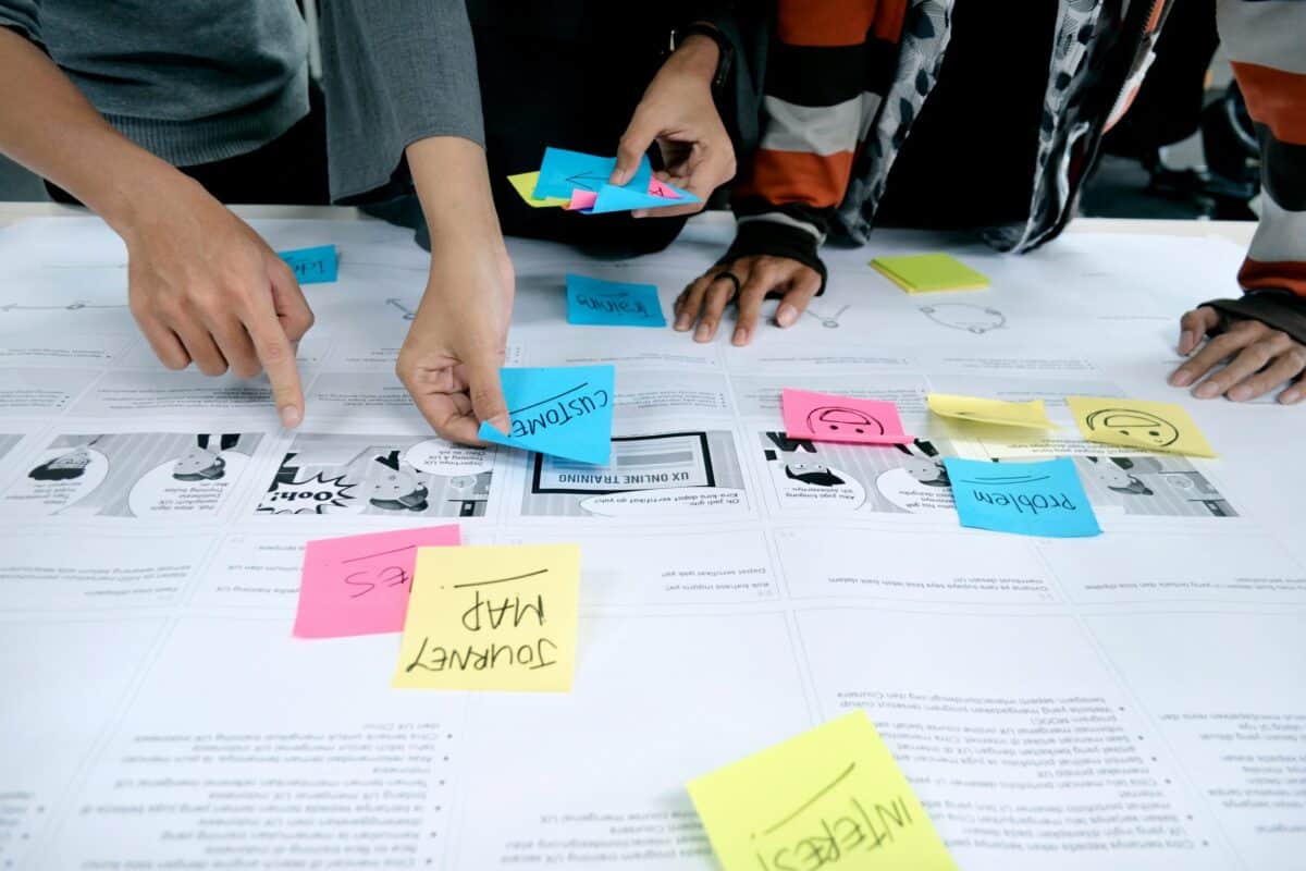 Group activity compiling a customer journey with paper printouts and sticky notes on a table.
