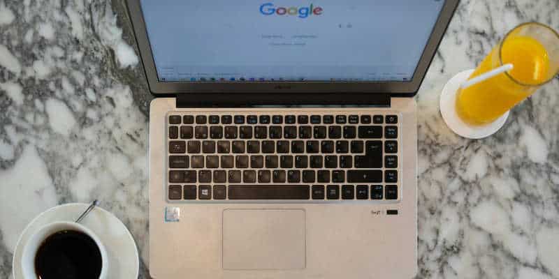 Laptop on a marble worktop with coffee and orange juice drinks